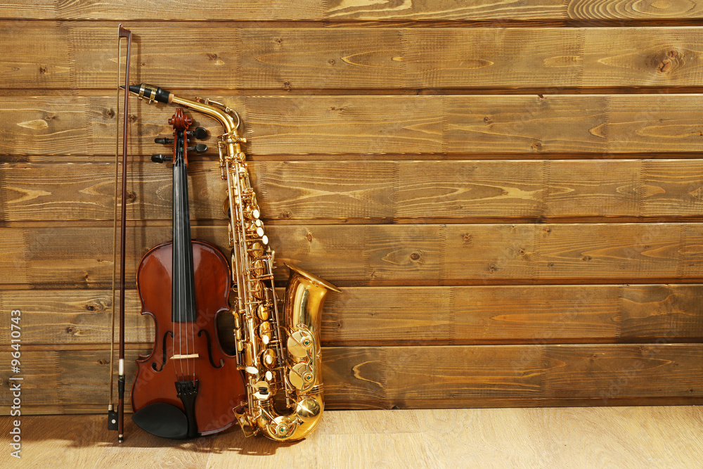 Naklejka premium Violin and saxophone on wooden background