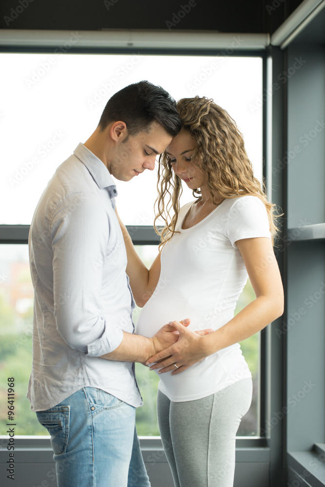 Naklejka premium Happy and young pregnant couple in studio, white background