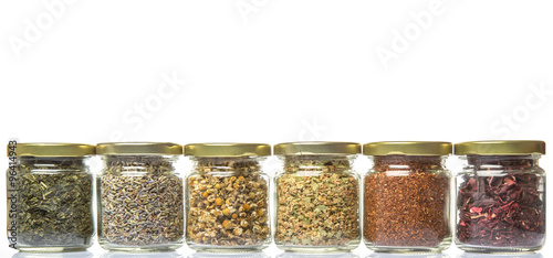 Dried herbal tea of Japanese green tea, lavender, chamomile, linden flower, hibiscus in mason jars over wooden background