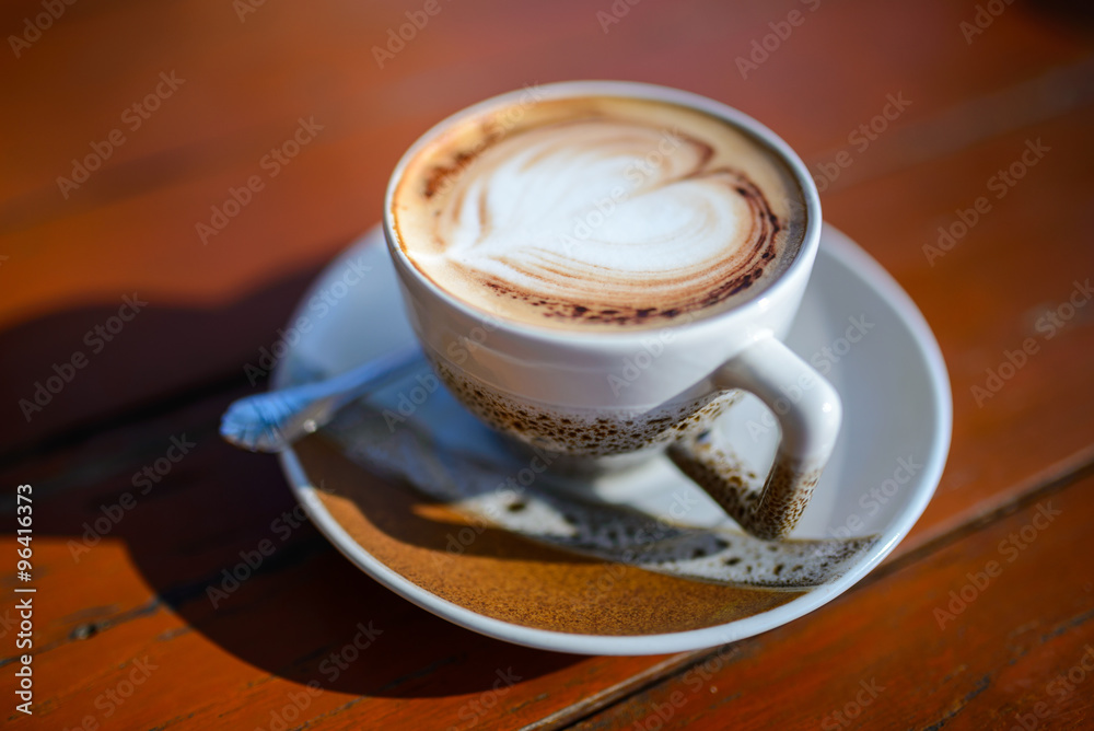 Fototapeta premium Cup of coffee with heart-shaped decoration on a wooden table
