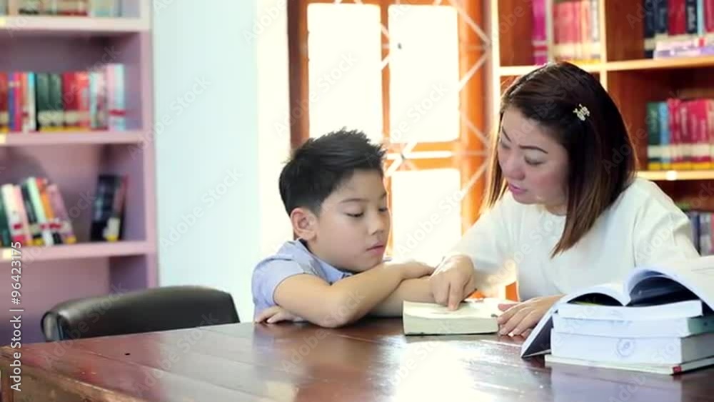 Reading with teacher - an elementary school boy reads aloud to her teacher Reading with teacher - an elementary school boy reads aloud to her teacher