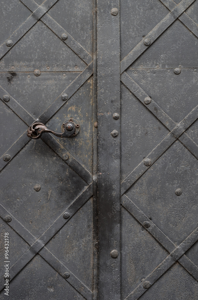 old iron door with handle, reinforced with steel belts and rivets