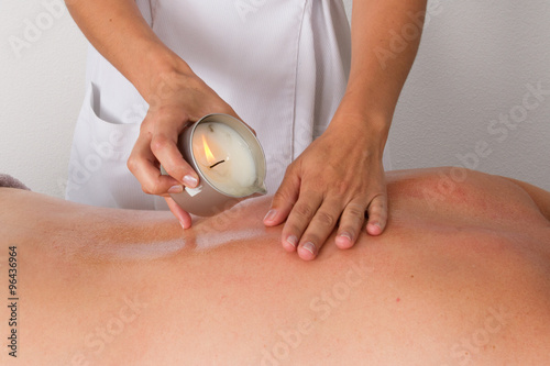 Woman receiving shoulder candle massage at Spa center