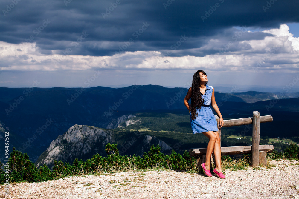 Naklejka premium woman relax on peak of mountain with rainy sky