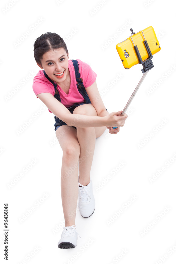 Young woman taking picture with smartphone selfie stick and sitting on the floor. Young woman taking picture with smartphone selfie stick and sitting on the floor.