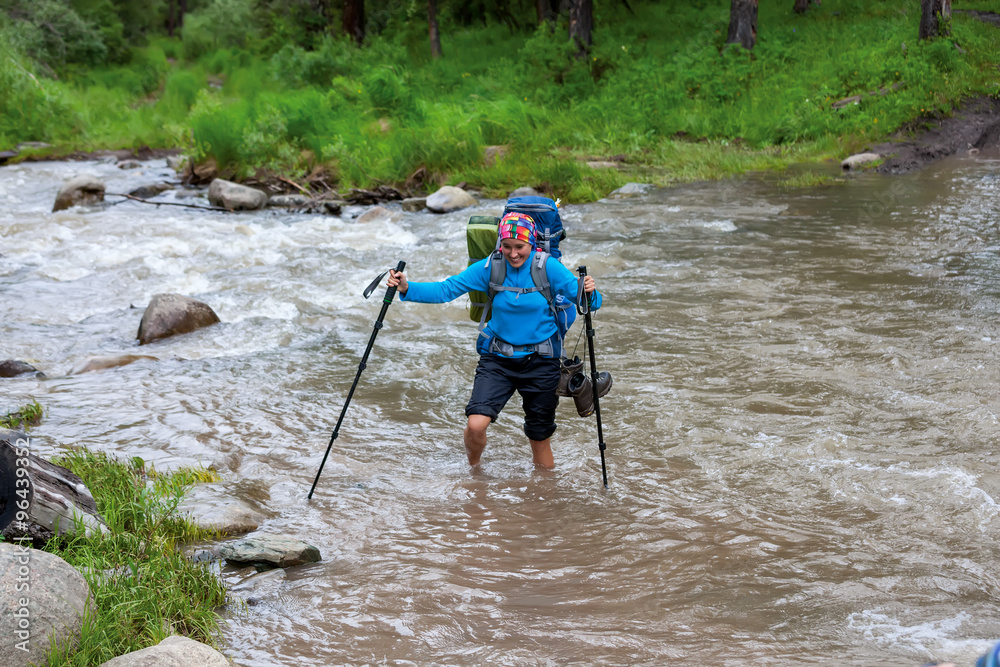 Woman is crossing mountain reiver on foot without shoes Woman is crossing mountain reiver on foot without shoes