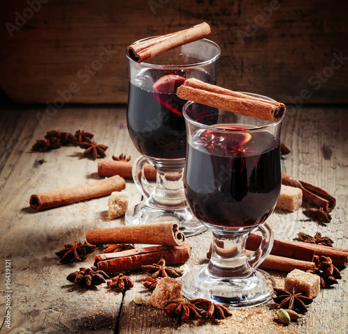 Hot mulled wine with spices on an old wooden background, selecti photo