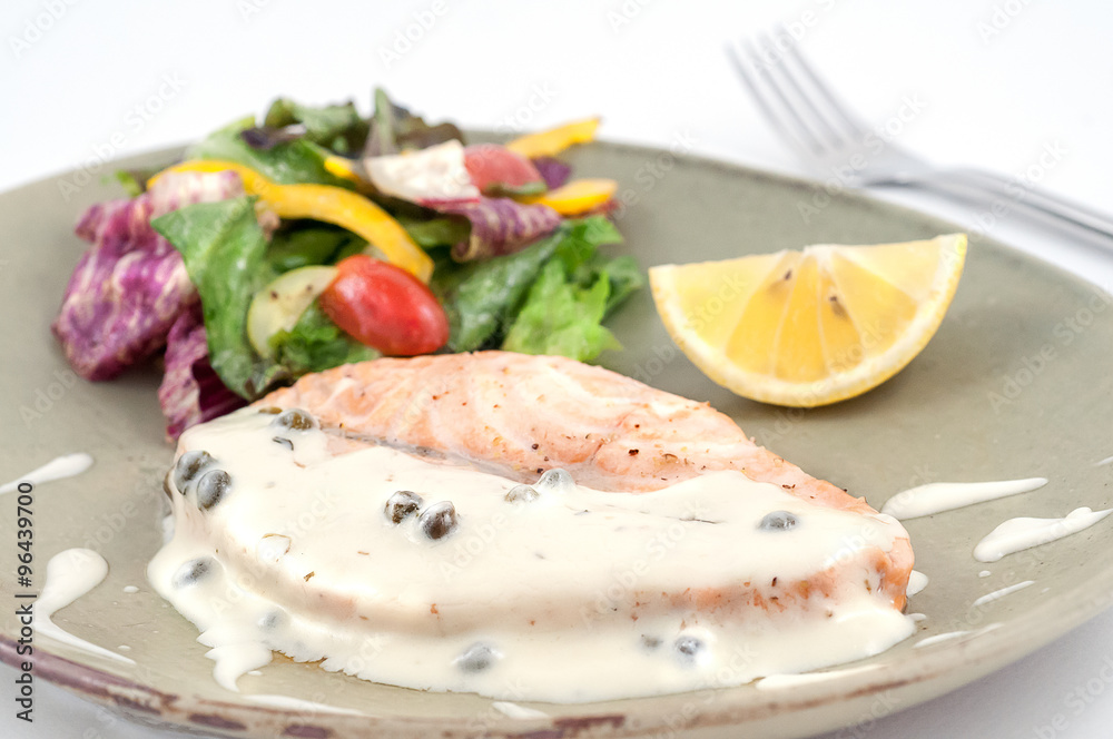 Grilled salmon with white sauce, vegetables and lemon isolated on white Grilled salmon with white sauce, vegetables and lemon isolated on white