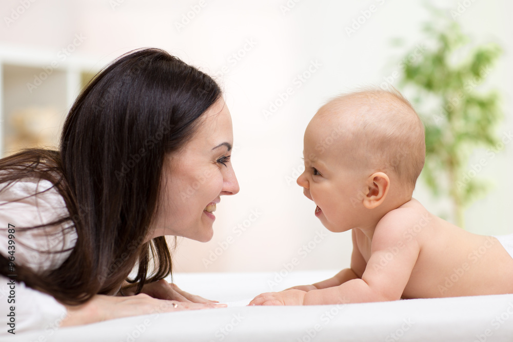 Mother playng with her baby. Woman and child is lying on bed Mother playng with her baby. Woman and child is lying on bed