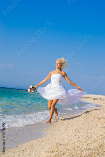 Beautiful young bride walking on the beach