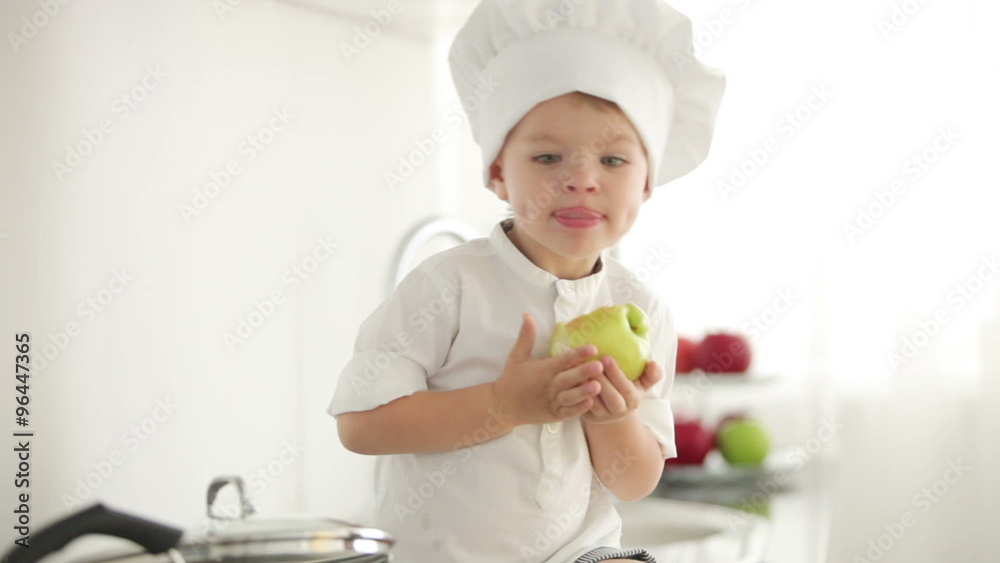Chef boy eating apple in kitchen and smiling Chef boy eating apple in kitchen and smiling
