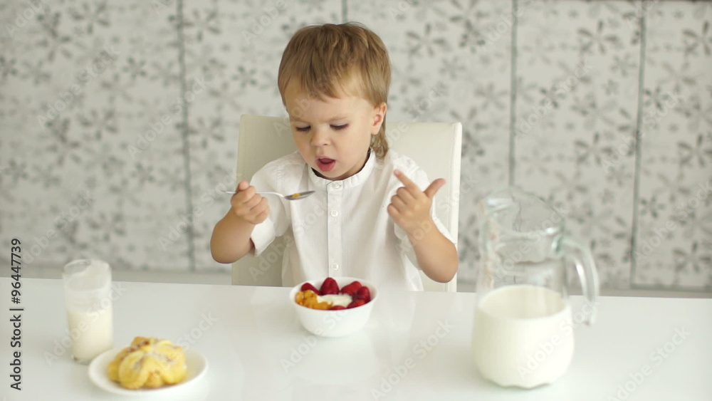 Cute boy eating yogurt with fruits and smiling Cute boy eating yogurt with fruits and smiling