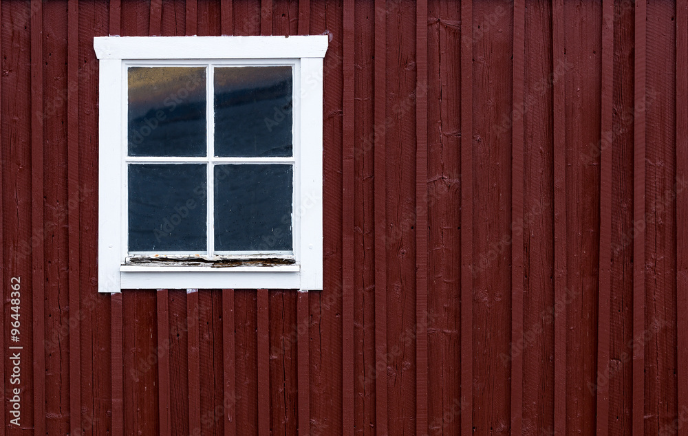 Red wooden wall with small window in white frame, typically Scandinavian living house architecture fragment