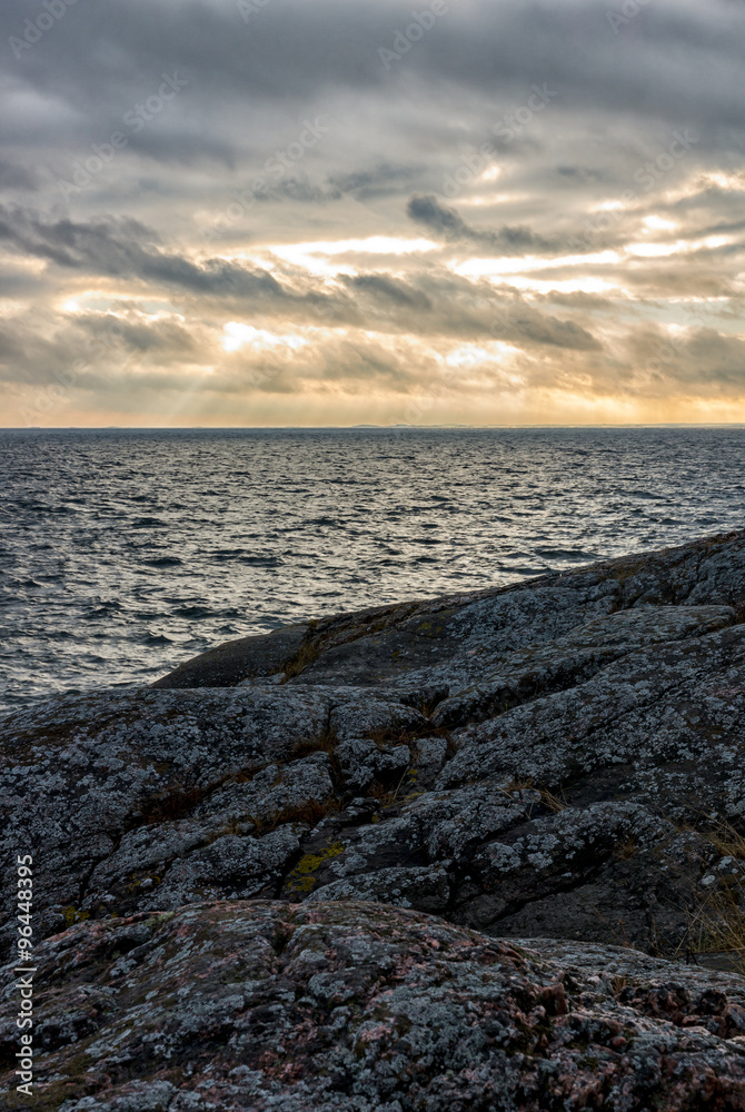 Obraz premium Sunset by coast with cloudy sky and sunbeams lightning trough the clouds