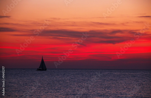 Sailboat on the ocean at bloody red sunset