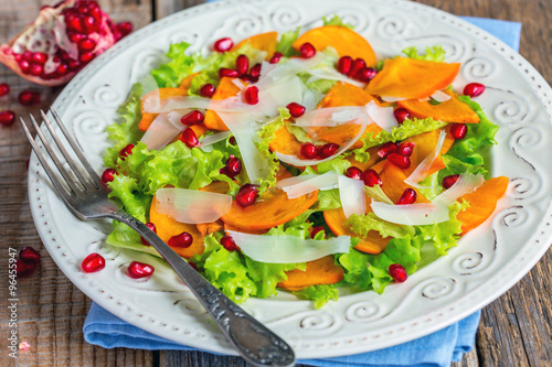 Salad with persimmon and pomegranate seeds close-up.