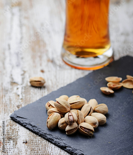 Pistachio nuts with beer on slate board.