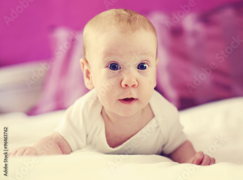 Cute smiling baby lying on bed