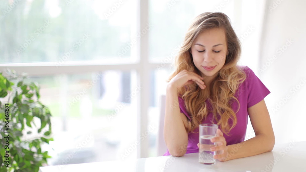 Attractive young woman sitting at table drinking water with smile Attractive young woman sitting at table drinking water with smile
