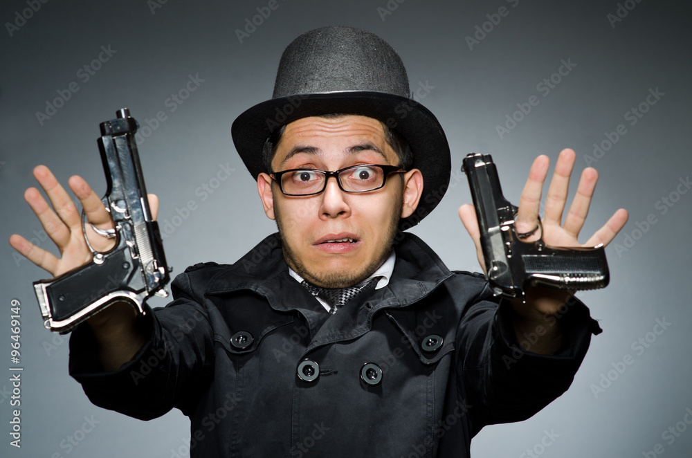 Criminal in black coat holding hadgun against gray Criminal in black coat holding hadgun against gray