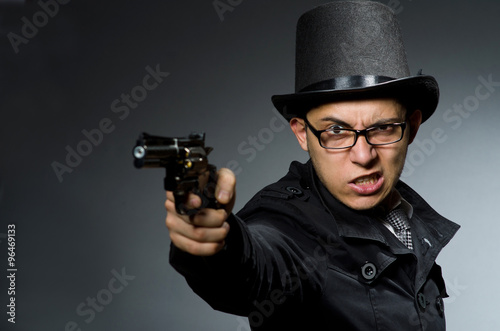 Criminal in black coat holding hadgun against gray © Elnur