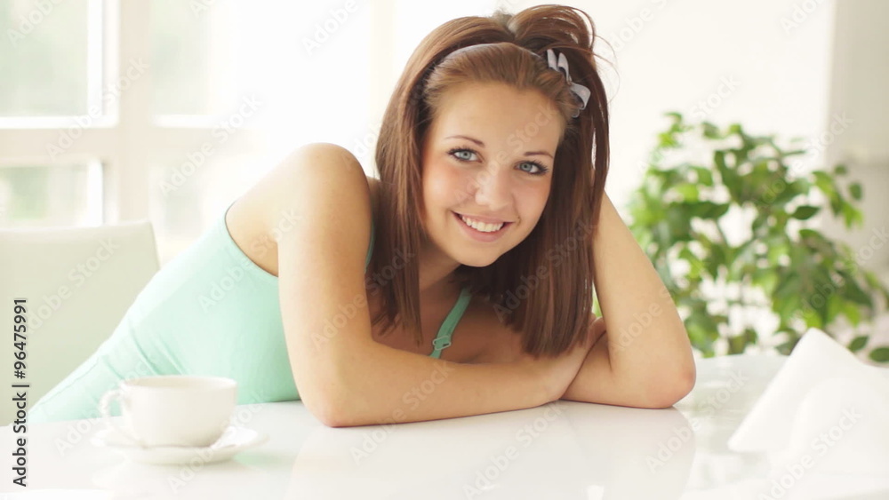 Pretty girl leaning on table and smiling at camera Pretty girl leaning on table and smiling at camera
