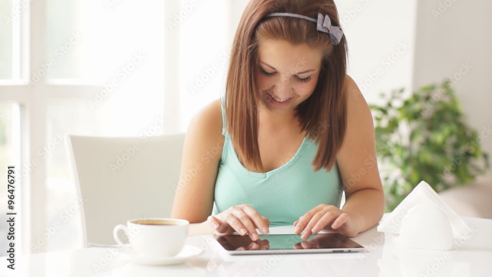 Young woman sitting at table using touch pad smiling and laughing at camera Young woman sitting at table using touch pad smiling and laughing at camera