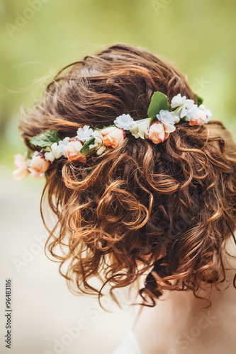 Closeup portrait of girl long wavy curly hair and flowers chaplet on head. Attractive young woman model in park outside, country village hippie style, no face, hidden face, bare shoulders