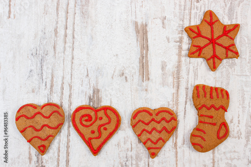 Fresh baked decorated gingerbread on old wooden background, christmas time