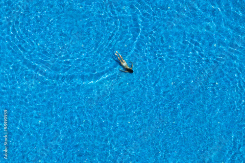 Woman swims in a swimming pool. View from above.