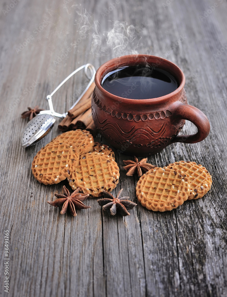 A cup of hot tea with cookies on a rustic wooden background A cup of hot tea with cookies on a rustic wooden background