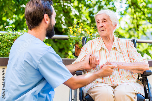 Pfleger hält Hand von Seniorin im Seniorenheim