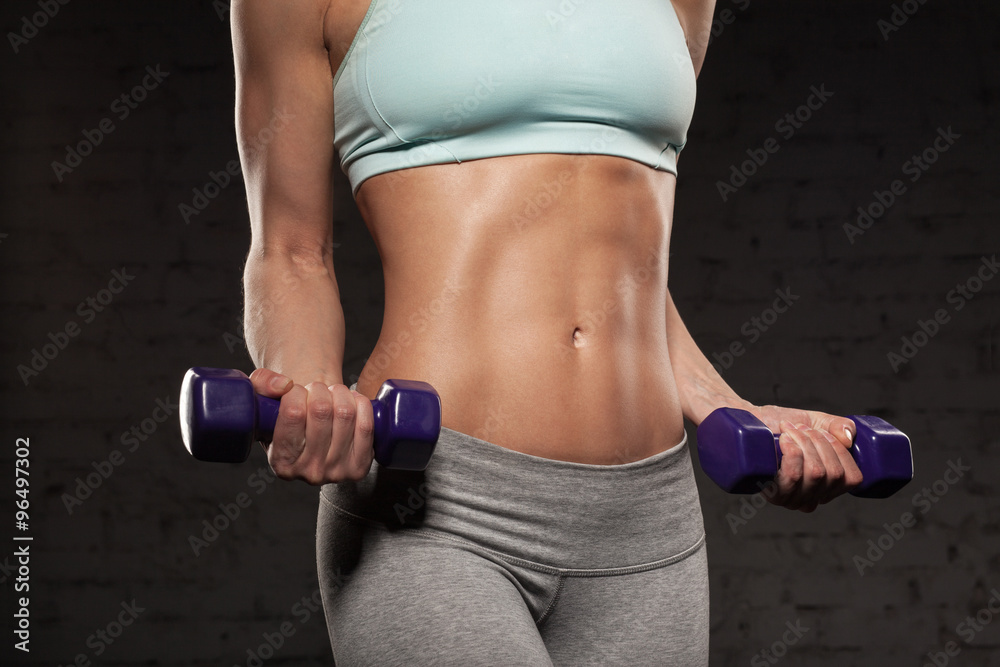 Fitness female woman with muscular body, do her workout with dumbbells, abs, abdominals Fitness female woman with muscular body, do her workout with dumbbells, abs, abdominals