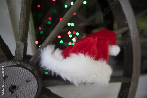 Santa hat on an old wooden wagon wheel with background lights