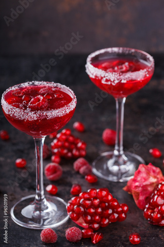 Red alcoholic cocktail with raspberry and pomegranate, in a glass glass on a black background. selective focus.