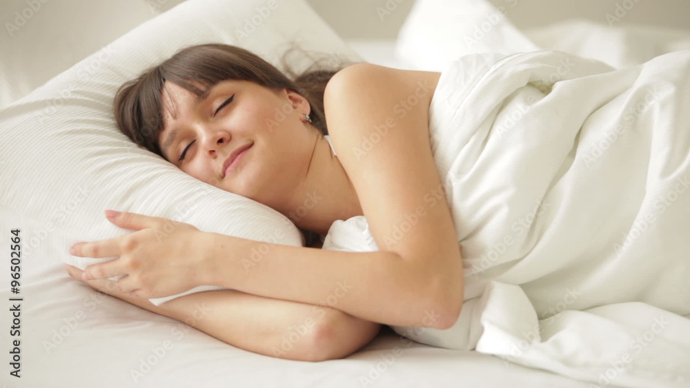 Pretty girl sleeping in bed hugging her pillow and smiling in her sleep Pretty girl sleeping in bed hugging her pillow and smiling in her sleep