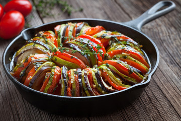 Traditional homemade vegetable ratatouille baked in cast iron frying pan healthy diet french vegetarian food on vintage wooden table background