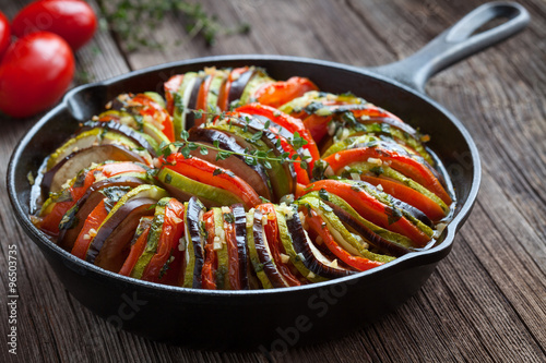 Traditional homemade vegetable ratatouille baked in cast iron frying pan healthy diet french vegetarian food on vintage wooden table background