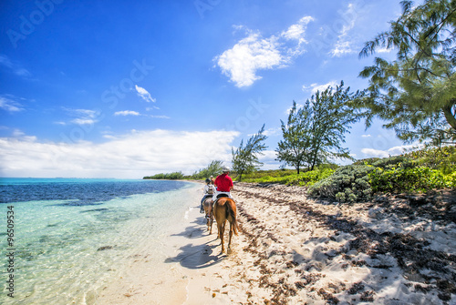 Фотография People riding on horse back at the Caribbean beach. Grand Cayman