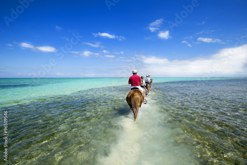 Tableau sur toile People riding on horse back at the Caribbean beach. Grand Cayman