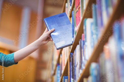 Students hand with smartwatch picking book from bookshelf photo