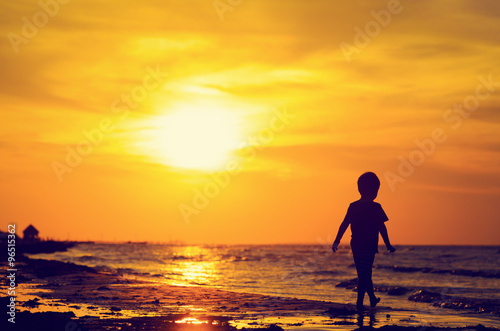 little boy walking on sunset beach