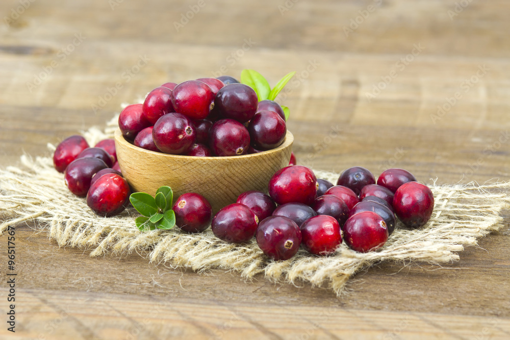 Cranberries in wooden bowl on wooden background