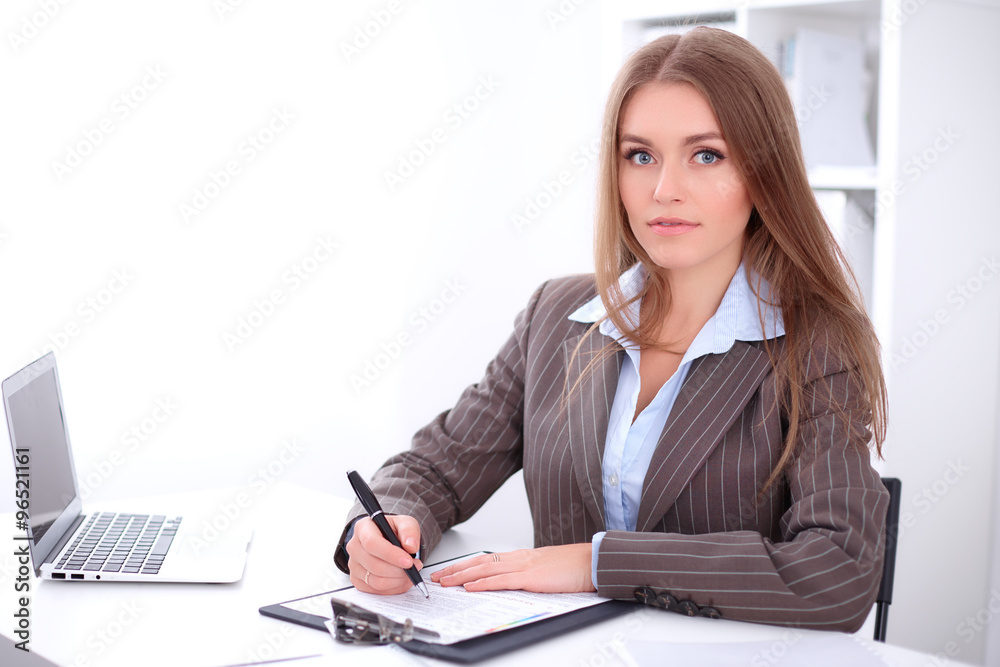 young business woman signing documents sitting at the desk on office background young business woman signing documents sitting at the desk on office background