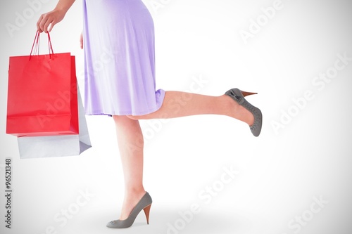 Mid section of woman in dress holding shopping bag