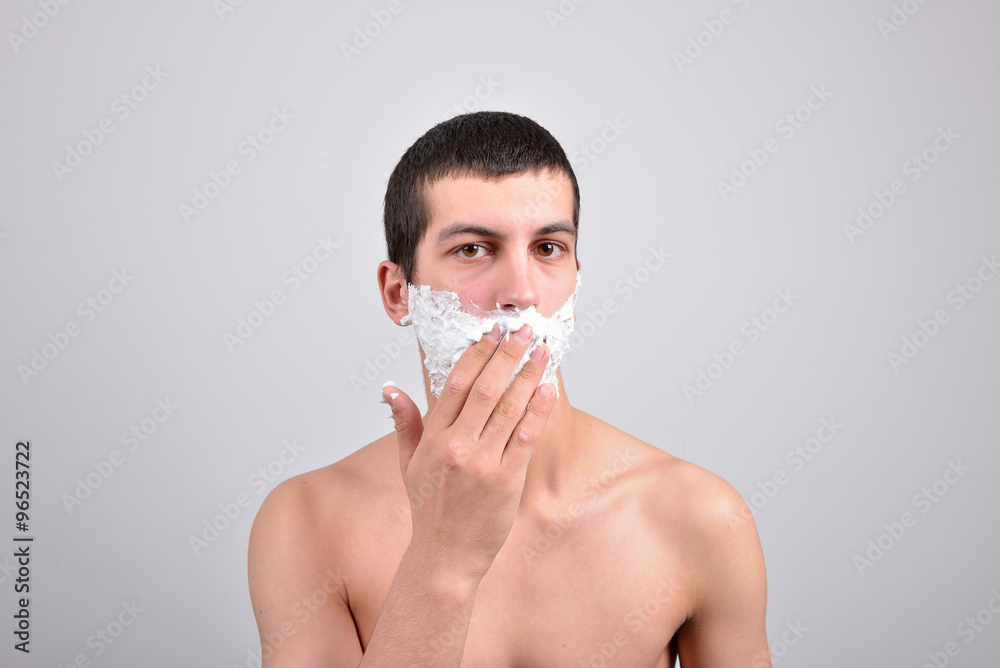 Closeup of a young man preparing to shave, he puts foam on his c