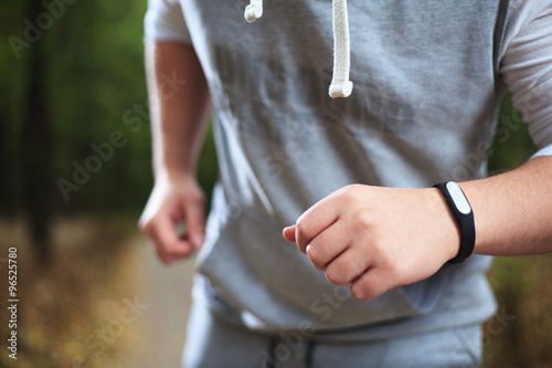 young man using fitness bracelet during morning run