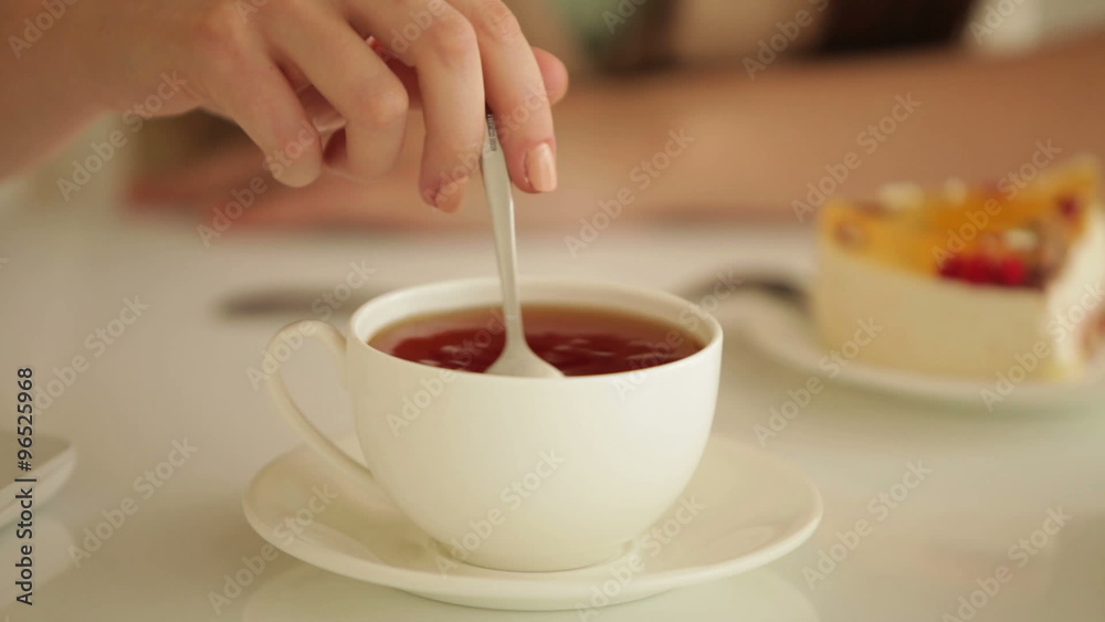 Young woman stirring tea with spoon Young woman stirring tea with spoon
