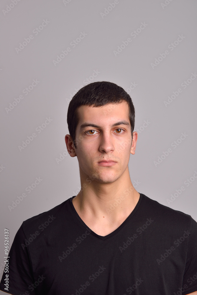 Portrait of a serious young man standing against grey background