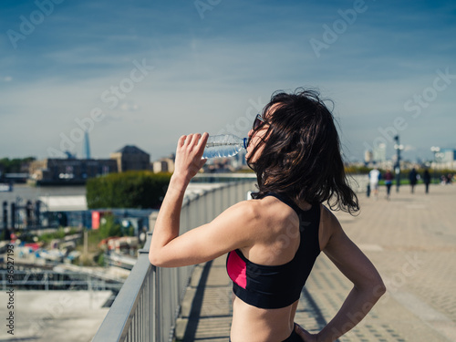Athletic young woman drinking after workout in city
